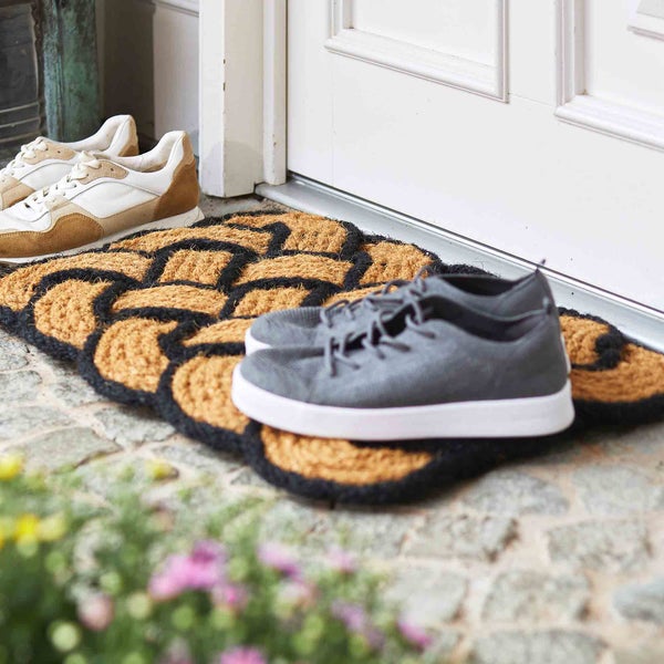 Fußmatte aus Kokosfaser mit Schuhen vor einer Haustür
