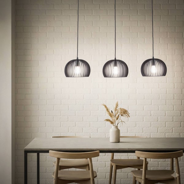 Drei Pendelleuchten über einem Esstisch mit Stühlen vor einer Ziegelwand
