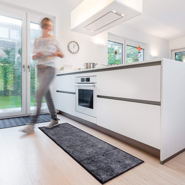 Moderne Küche mit grauer Küchenmatte und Person im Hintergrund