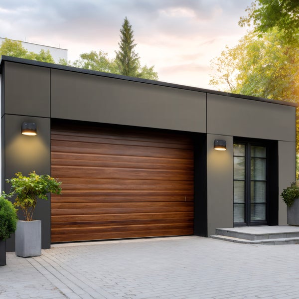 Moderne Garage mit Holzsektionaltor, Außenbeleuchtung und gepflasterter Zufahrt