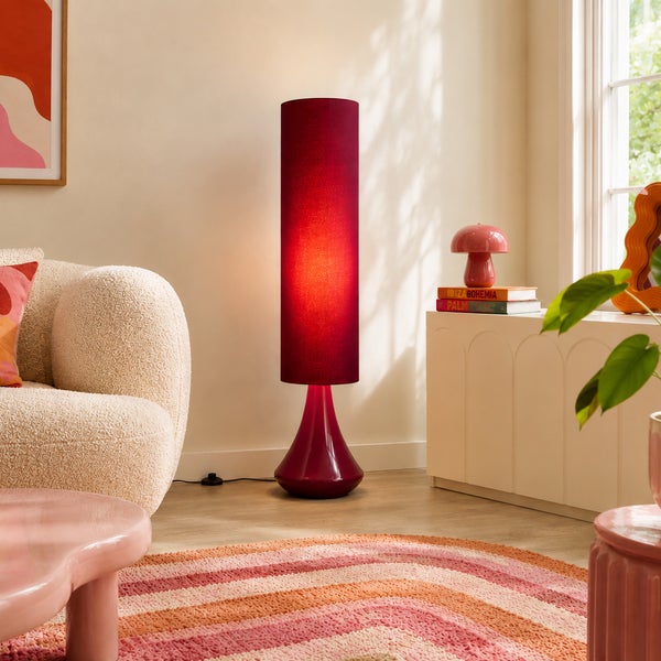 Moderne Stehleuchte mit zylindrischem Textilschirm in einem Wohnzimmer mit gemütlichem Sessel und Beistellmöbeln.