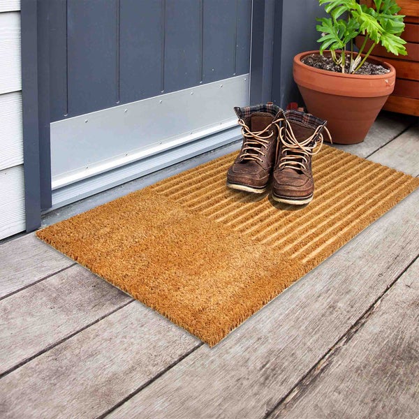 Fußmatte aus Kokosfasern mit Stiefeln vor einer Haustür