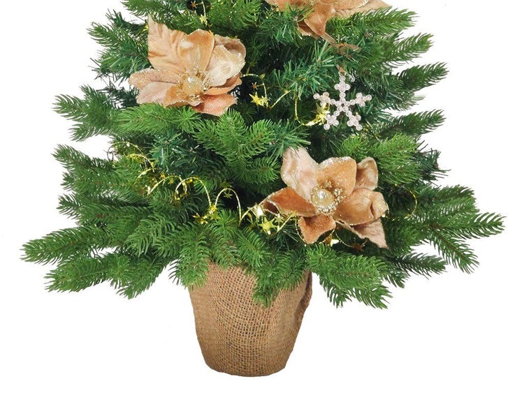 Künstlicher Weihnachtsbaum in Jutesack dekoriert mit Blüten, Sternengirlande und Schneeflockenanhänger.