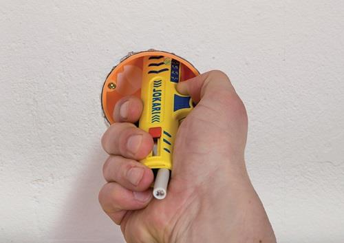 Hand die eine Jokari Abisolierzange an einer Elektrodose verwendet