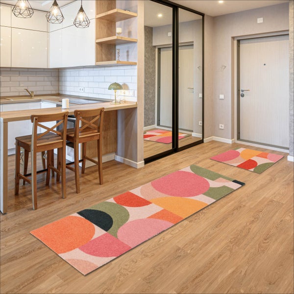 Moderne Wohnungseinrichtung mit offener Küche, Holzfußboden und zwei Teppichläufern mit geometrischem Muster.