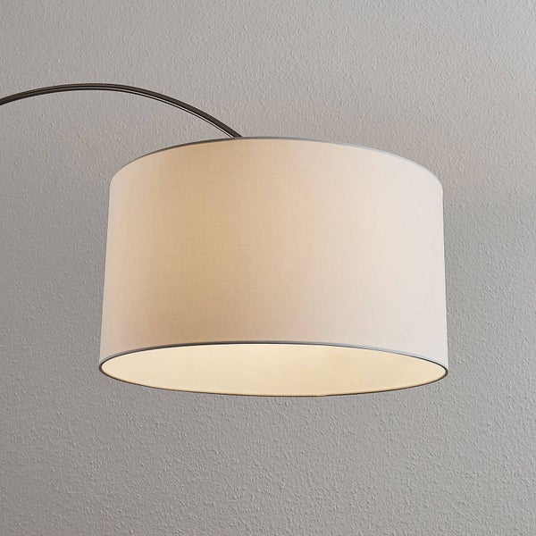 Zylindrischer Textillampenschirm einer Bogenlampe mit gebogenem Metallarm.