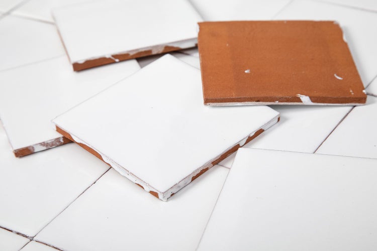 Quadratische, weiße Fliesen mit einer braunen Fliese.