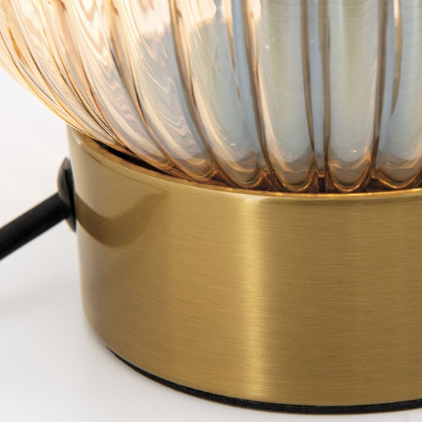 Detailansicht einer Tischleuchte mit geripptem Glasschirm und goldfarbenem Sockel.