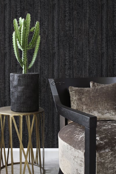 Dekoratives Zimmer mit Kaktus in einem Topf auf einem Beistelltisch und einem Sessel vor einer Wandtapete.