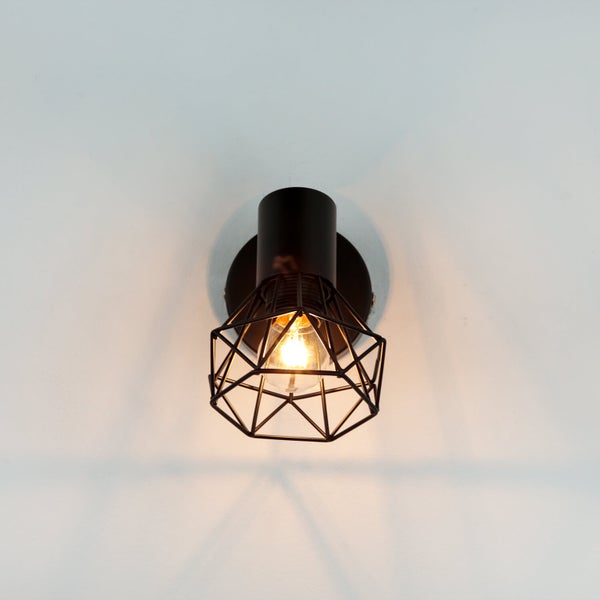 Schwarze Wandleuchte mit geometrischem Lampenschirm und Glühbirne.