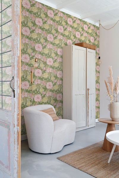 Wohnzimmer mit floraler Tapete, Sessel und Schrank