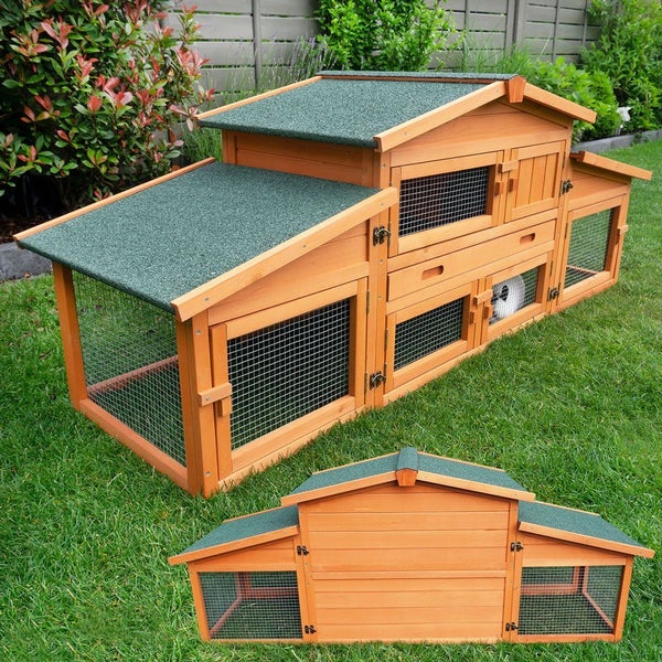 Mehrstöckiger Kleintierstall aus Holz mit integriertem Freigehege und wetterfestem Bitumendach auf einer Rasenfläche.
