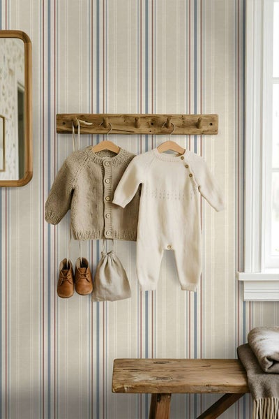 Tapete mit Streifenmuster in einem Kinderzimmer mit einer Holzgarderobe und aufgehängter Babykleidung sowie einer Holzbank.