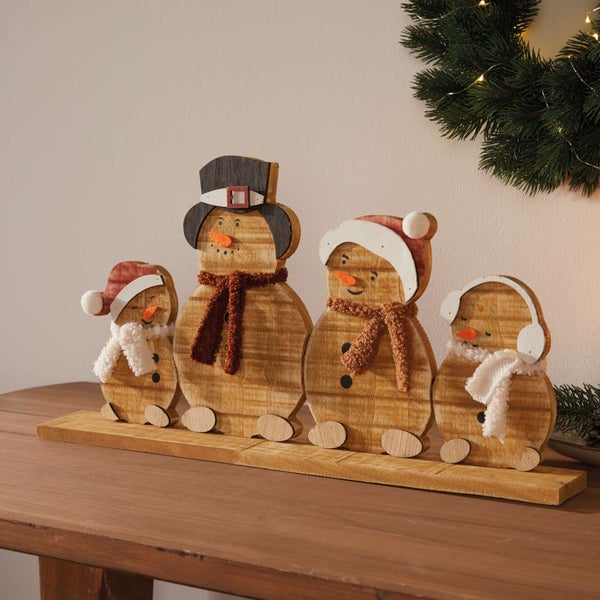 Dekorative Holzfiguren einer Schneemannfamilie auf einem Holzbrett