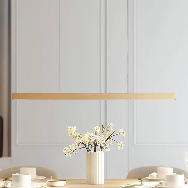 Moderne lineare LED-Pendelleuchte in Goldoptik über einem gedeckten Esstisch mit Blumen.