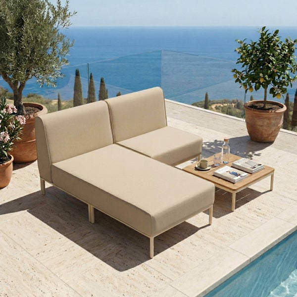 Modernes Garten-Lounge-Set auf einer hellen Steinterrasse mit Pool und Meerblick. Modulares Sofa mit beigen Polstern und ein flacher Holztisch.