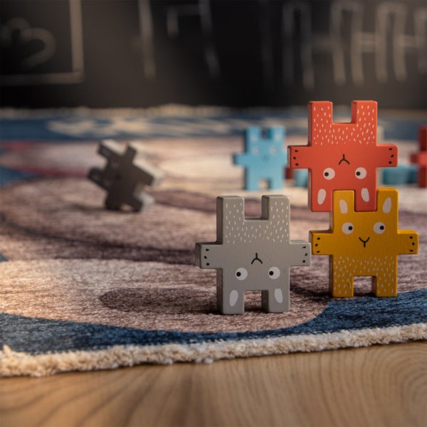 Stapelspiel aus Holz mit bunten Tierfiguren auf einem Teppich für Kinder.