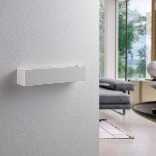 Eine schlichte weiße rechteckige Wandleuchte an einer Wand in einem modernen hellen Wohnzimmer.