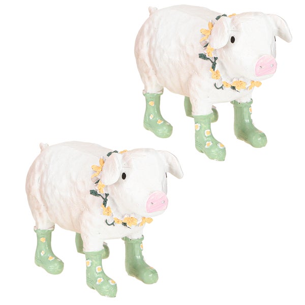 Zwei Schweinefiguren mit Blumenkränzen und Gummistiefeln als Gartendekoration
