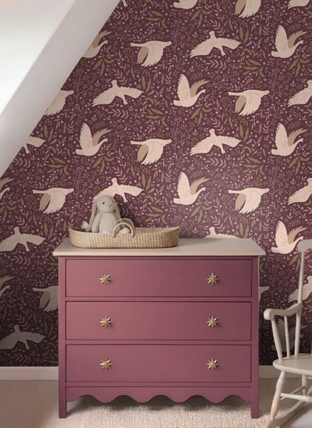 Vliestapete mit fliegenden Vögeln und Blumenmuster in einem Kinderzimmer hinter einer Kommode mit drei Schubladen und einem Plüschtier.