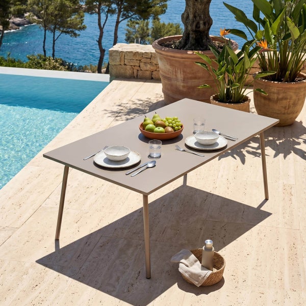 Moderner rechteckiger Gartentisch auf Steinterrasse am Pool, gedeckt für zwei Personen, mit Pflanzen und Meerblick, hell und organisiert.