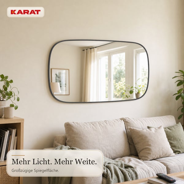 Wandspiegel mit abgerundeten Ecken und Rahmen über einem Sofa in einem hellen Wohnzimmer, Karat Logo.