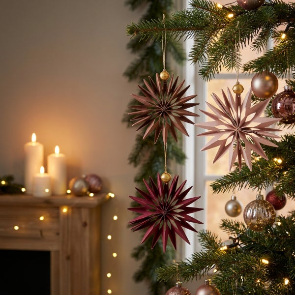 Weihnachtsdekoration Sterne aus Papier hängend an einem Tannenbaum mit Lichtern im Hintergrund