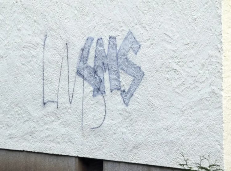Graffiti auf einer verputzten Hauswand.