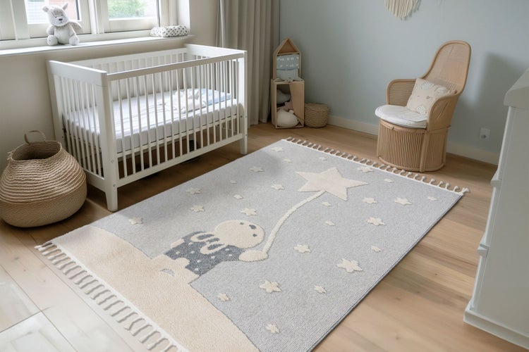 Ein Kinderteppich mit Hasenmotiv und Sternen liegt in einem hell eingerichteten Kinderzimmer mit Babybett und Rattan Sessel.