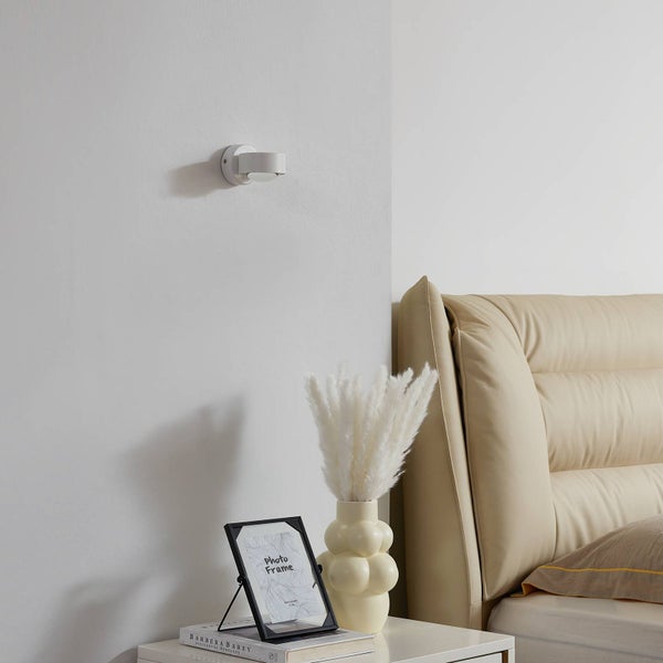 Wandleuchte über Nachttisch neben Bett.