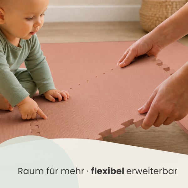Ein Kleinkind schaut beim Verlegen einer steckbaren Puzzlematte zu, die als flexibler Spielteppich für Kinder dient.