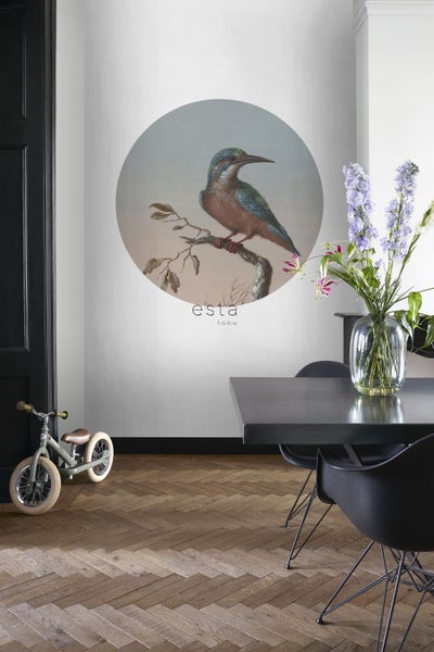 Szene eines Esszimmers mit einem Wandbild von Esta Home, das einen Vogel auf einem Ast zeigt, sowie einem Tisch, Stühlen und einem Kinderfahrrad