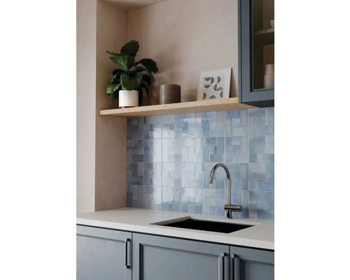 Moderne Küche mit Fliesenspiegel aus blauen glänzenden Quadratfliesen, weißer Arbeitsplatte, schwarzer Spüle und hoher Chromarmatur.
