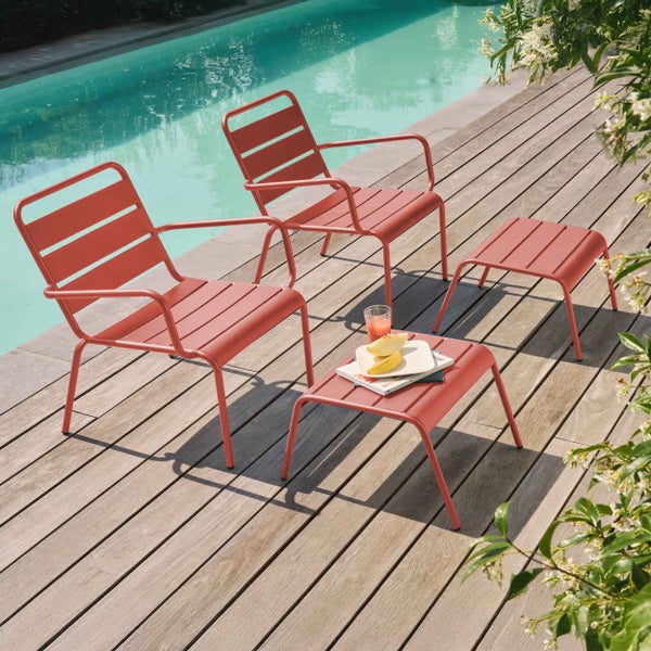 Modernes Set aus zwei Garten-Loungesesseln und zwei Beistelltischen aus Metall mit Lattenstruktur auf einer hellen Holzterrasse am Pool.