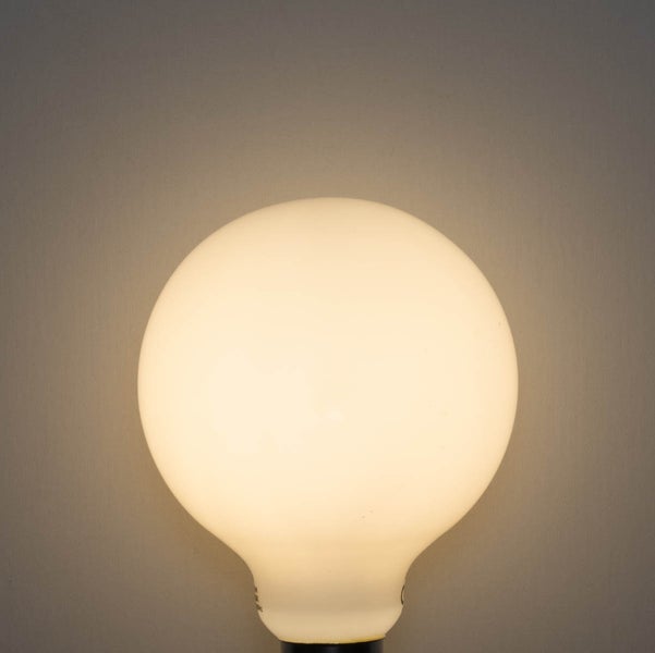 Eingeschaltete Globe-Lampe aus mattem Glas mit warmweißem Licht.