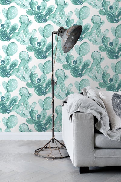 Dekoratives Zimmer mit Kaktusmuster-Tapete, Stehlampe und Sofa.