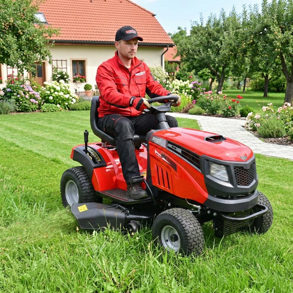 Mann fährt Rasentraktor im Garten