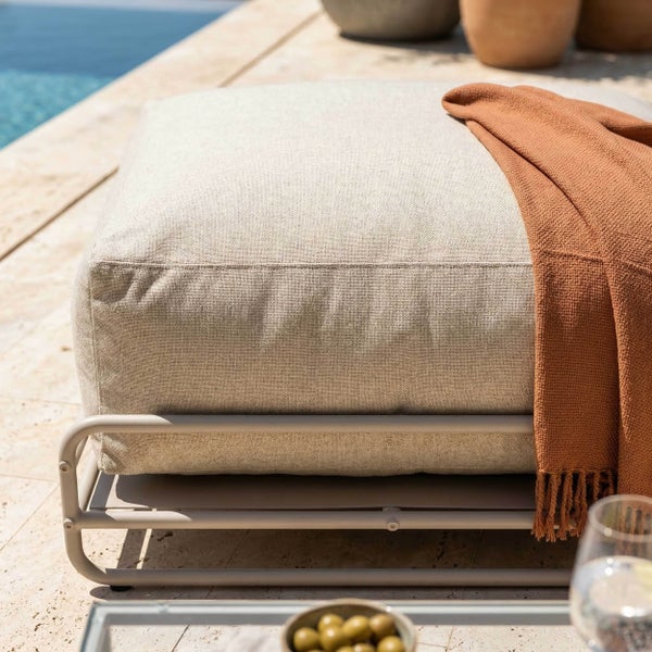 Outdoor-Sitzkissen auf hellem Metallgestell am Pool mit orangefarbener Decke auf Steinplatten.