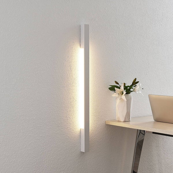 Moderne vertikale LED-Wandleuchte in minimalistischem Design an einer strukturierten Wand, die warmes Licht spendet, neben einem Schreibtisch.