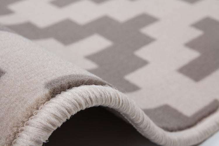 Teppich mit geometrischem Muster und gekettelter Kante