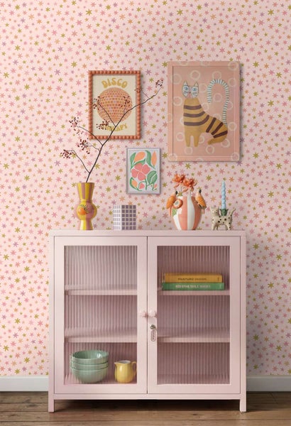 Wohnraum mit Tapete mit Sternenmuster, einem Schrank mit Rillenglasfronten sowie Wandbildern und Dekorationsgegenständen im modernen Stil.