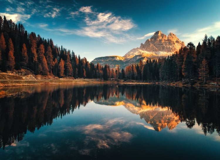 Fototapete mit Berglandschaft, See und herbstlichen Wäldern, Spiegelung des Gebirges im Wasser unter blauem Himmel.