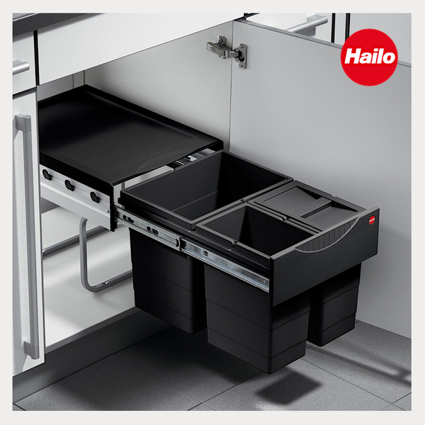 Ausgezogenes Hailo Abfalltrennsystem mit drei schwarzen Kunststoffbehältern auf Metallschienen in einem weißen Küchenunterschrank. Hailo Logo.