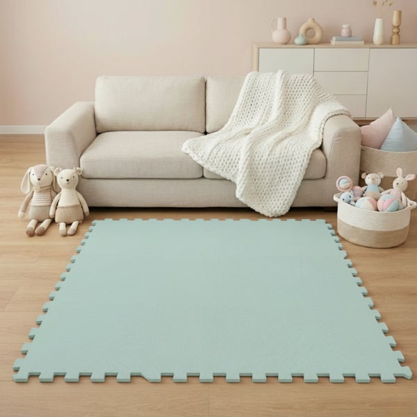 Puzzle-Spielmatte aus Schaumstoff auf Holzboden in einem hellen, geordneten Kinderzimmer mit einem Sofa und Stofftieren.