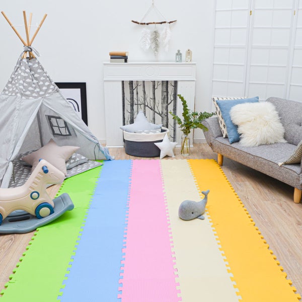 Kinderspielzimmer mit mehrfarbiger Puzzlematte als Bodenbelag, Spielzelt, Schaukelpferd und modernem Sofa.
