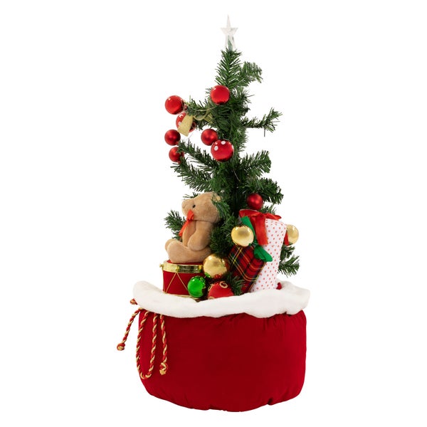 Geschmückter künstlicher Weihnachtsbaum in einem Weihnachtssack mit Teddybär und Geschenken als Dekoration