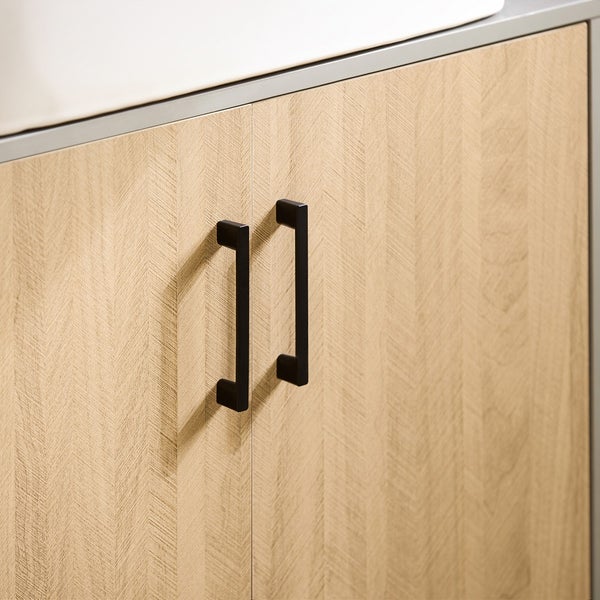Detailaufnahme eines Waschtischunterschranks mit zwei schwarzen Griffen und einer hellen Holzoberfläche