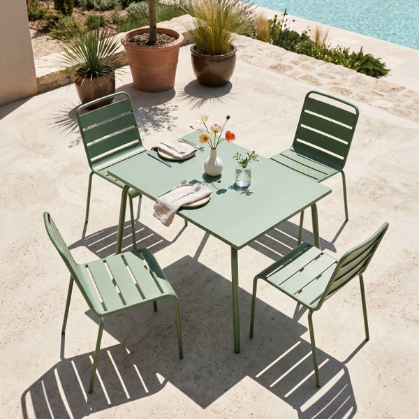 Modernes Gartenmöbel-Set aus Metall bestehend aus einem quadratischen Tisch und vier Stapelstühlen auf einer Terrasse neben einem Pool.