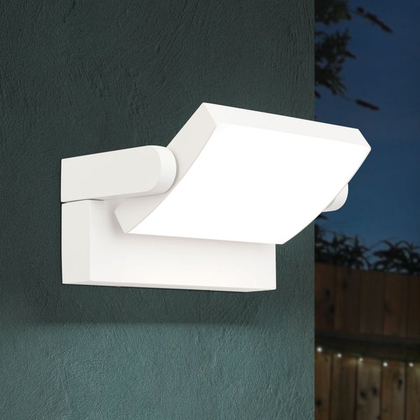 Moderne verstellbare LED-Außenwandleuchte an einer strukturierten Fassade bei Dämmerung leuchtend.