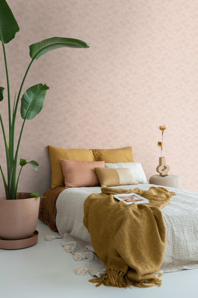 Ein Schlafzimmer mit einem Bett, Kissen, einer Decke, einer Pflanze und einer gemusterten Tapete